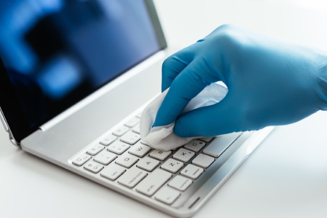 Techniker säubert die Tastatur eines Laptops